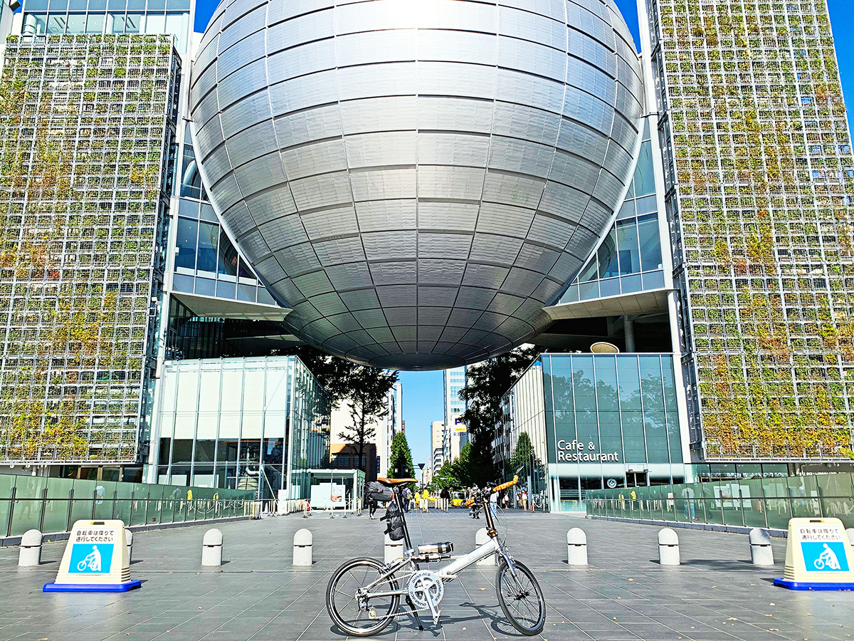 名古屋市科学館の建物のプラネタリウム部分の前に自転車を置いて撮影した写真